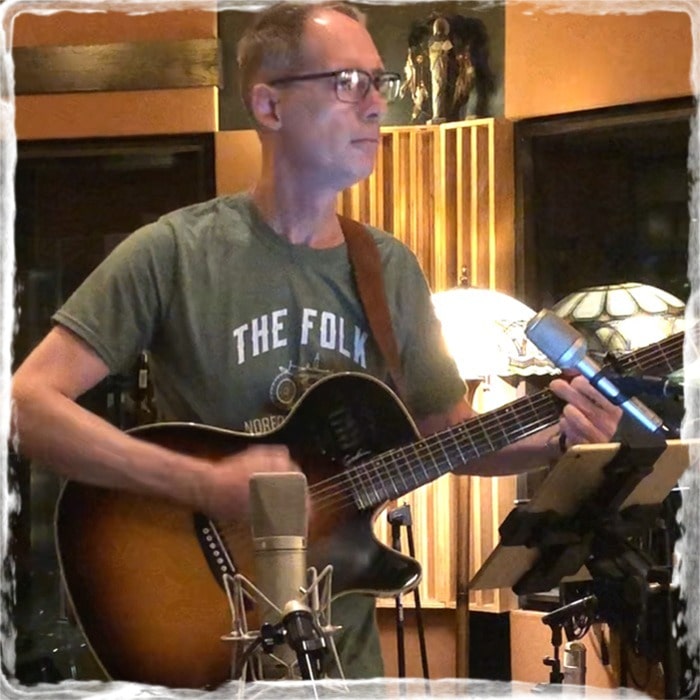 Jon playing guitar in a recording studio